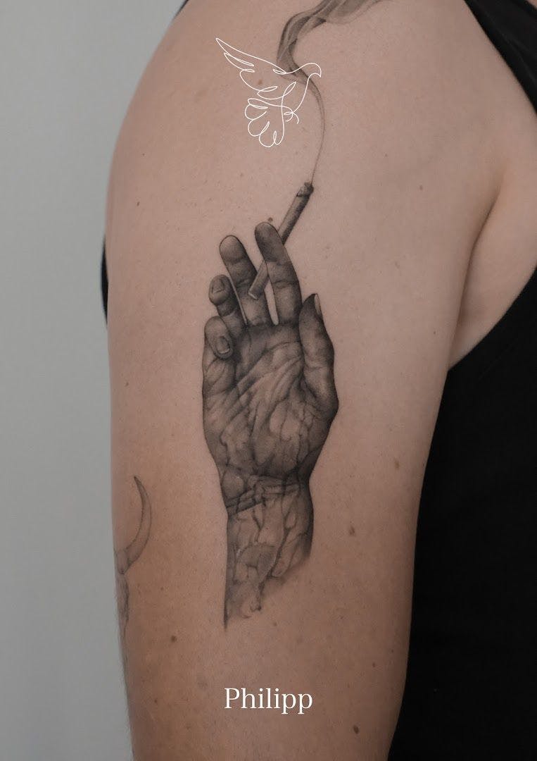 a woman's arm with a narben tattoo of a hand holding a cigarette, berlin, germany