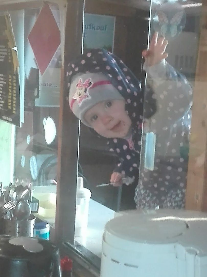 a little girl in a kitchen with a big mirror