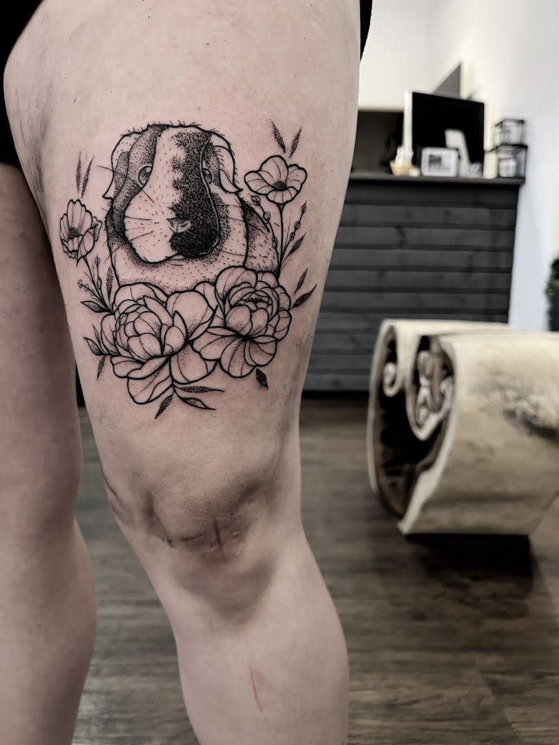 a narben tattoo of a dog with flowers on the thigh, düsseldorf, germany